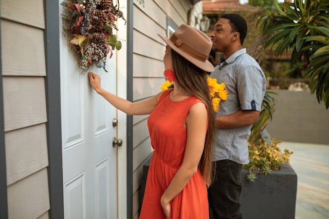 Two people knocking on the front door of a house